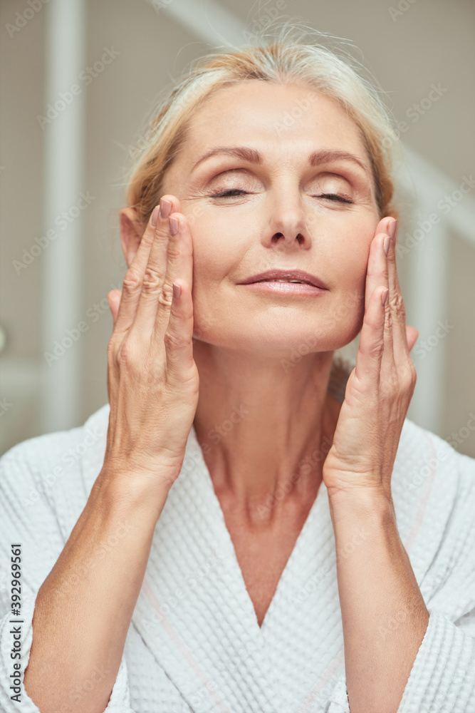 Happy middle aged caucasian woman making facial massage Happy middle aged caucasian woman making facial massage