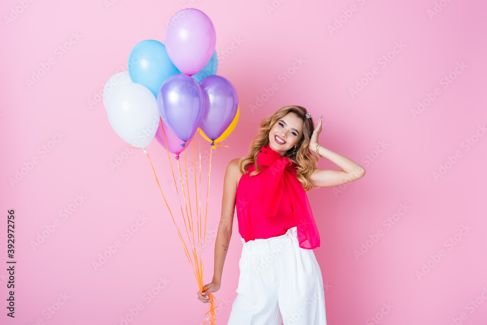 elegant happy woman in crown with balloons on pink background