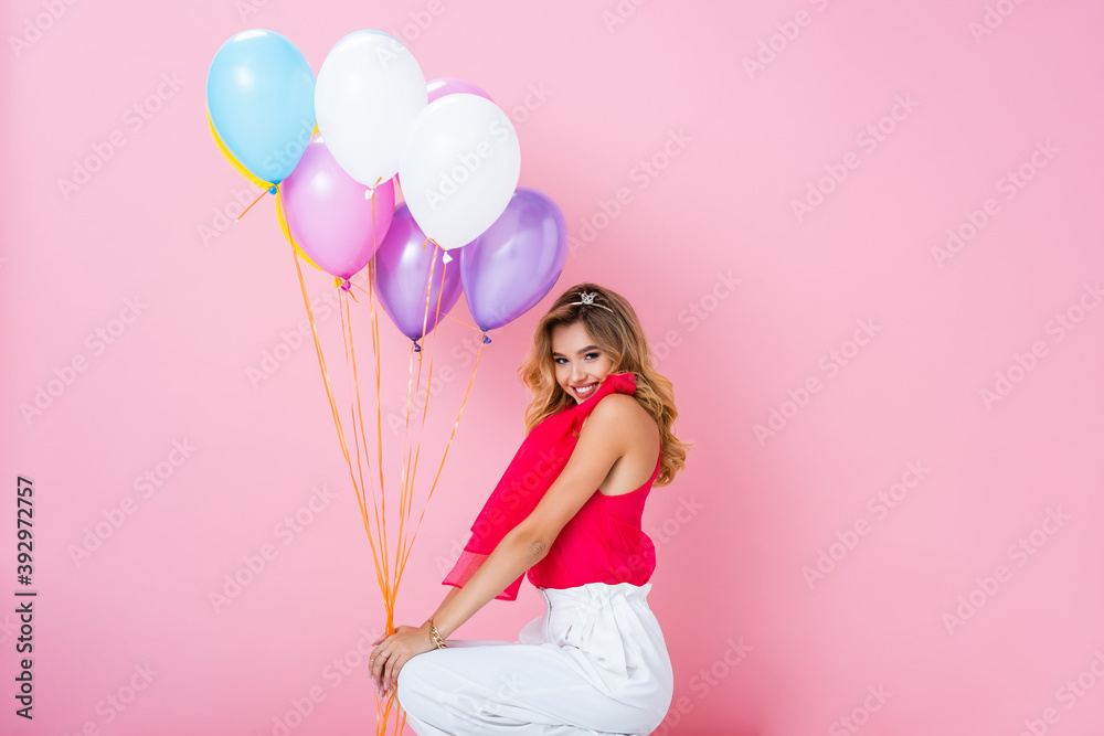 elegant happy woman in crown with balloons on pink background elegant happy woman in crown with balloons on pink background