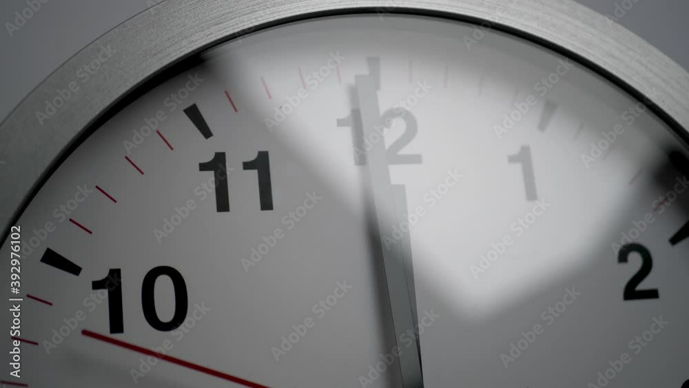 Close up of a white ticking clock on white background, pointing midnight, window reflection