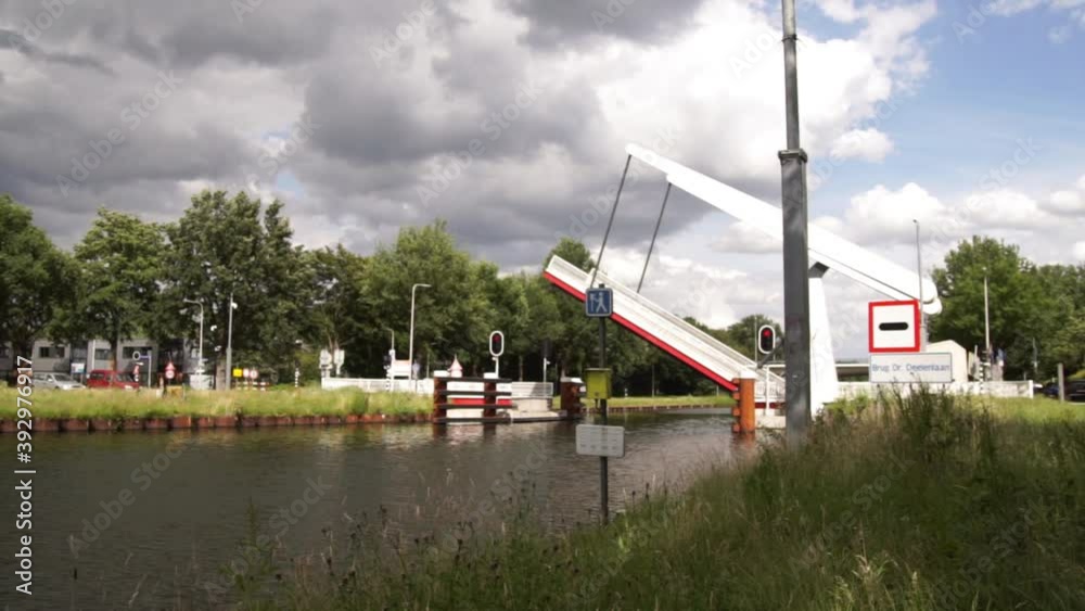 Dutch draw bridge lifting to let the boat come through the canal in Tilburg city, the Netherlands. Dutch draw bridge lifting to let the boat come through the canal in Tilburg city, the Netherlands.