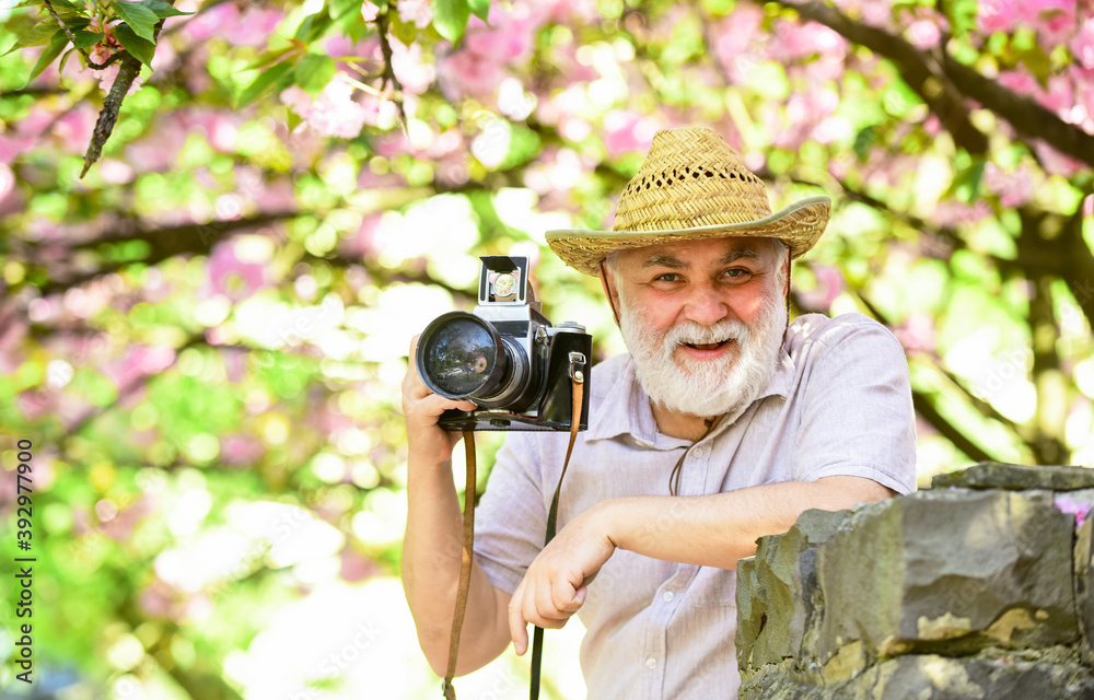 Retirement travel. Capturing beauty. Photographer in blooming garden. Senior man hold professional camera. Photography courses. Travel and tourism. Happy grandfather. Spring holidays. Travel photo