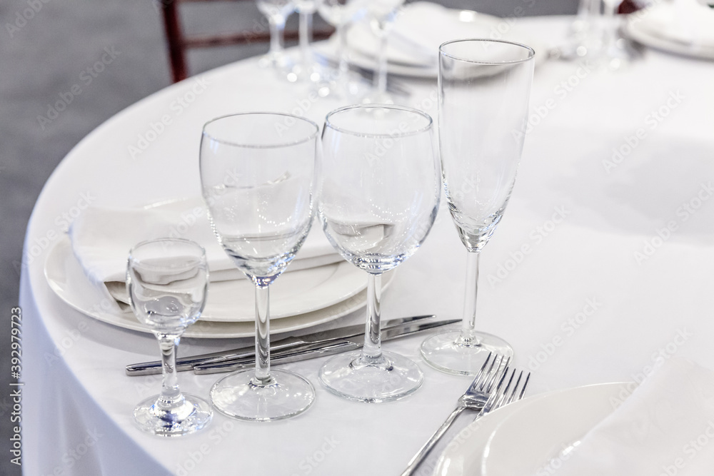 Fancy table set for dinner with napkin glasses in restaurant, luxury interior background. Wedding elegant banquet decoration and items for food arranged by catering service on white tablecloth table.
