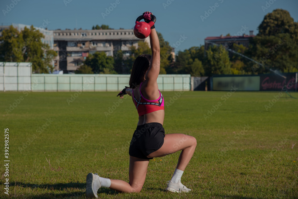 Push ups or press ups exercise by young woman. Girl working out on grass crossfit strength training in the glow of the morning sun against a white sky with copyspace.