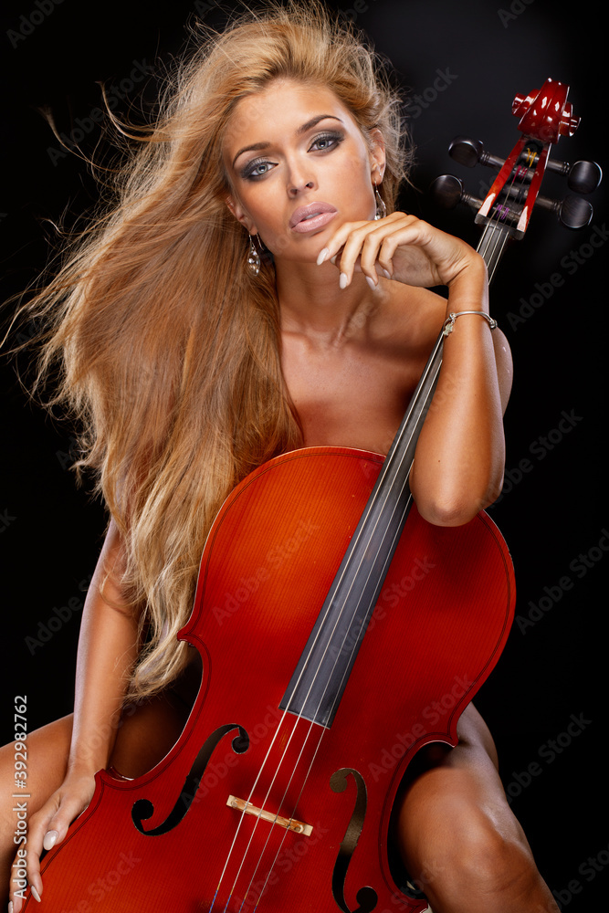Portrait of beautiful sexy nude blonde girl with tanned body sensual posing with cello.