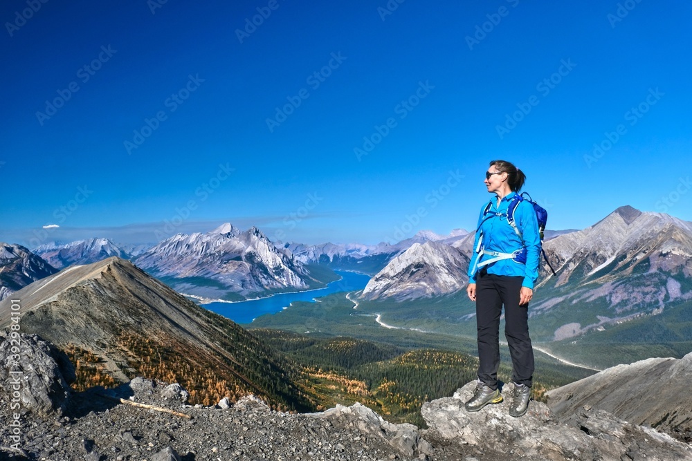  Middle age caucasian woman hiker on mountain top relaxing and enjoying view of lake and mountains in Canadian Rockies. Alberta. Canada