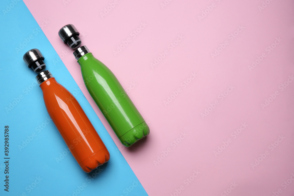Modern thermo bottles on color background, flat lay. Space for text Modern thermo bottles on color background, flat lay. Space for text