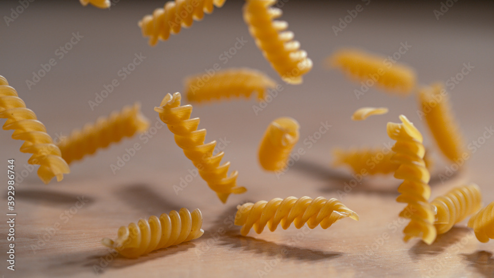 MACRO: Delicious fusilli pasta is scattered across a wooden kitchen counter. MACRO: Delicious fusilli pasta is scattered across a wooden kitchen counter.
