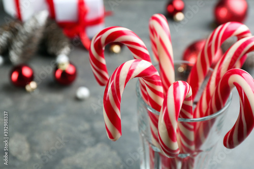 Many sweet candy canes in glass on table, closeup. Traditional Christmas treat