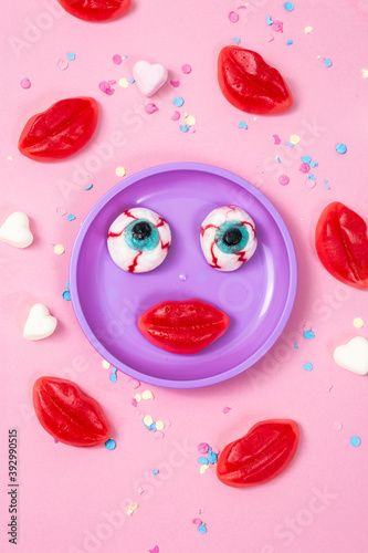 Red fruit chewing marmalade in the shape of a lips on a pink background. Flat lay, top view.