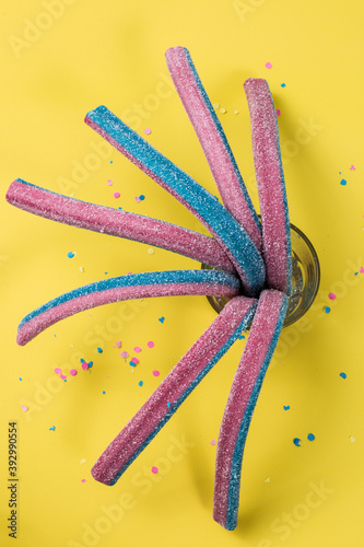 Rainbow chewable candy gums on yellow background. Flat lay, top view.