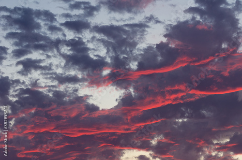 Red and dark clouds against a light blue sky. Image useful as graphic resources. Sky background and texture.