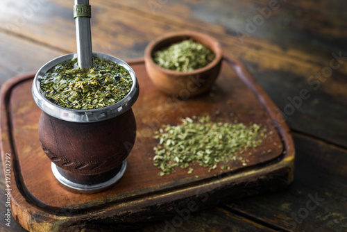 Traditional Argentinian yerba mate tea in a calabash gourd with bombilla stick against wooden background