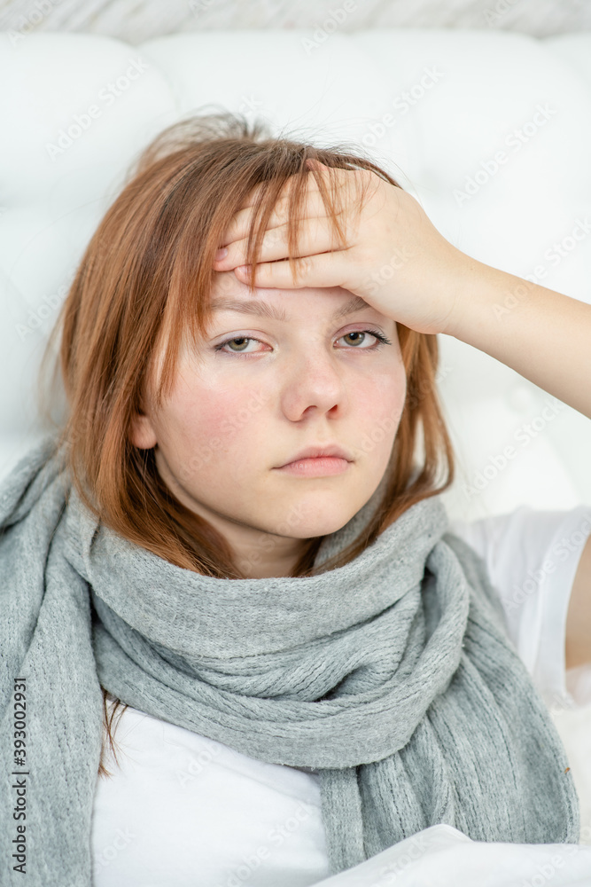 Sick girl on the bed touches her forehead checking the temperature Sick girl on the bed touches her forehead checking the temperature