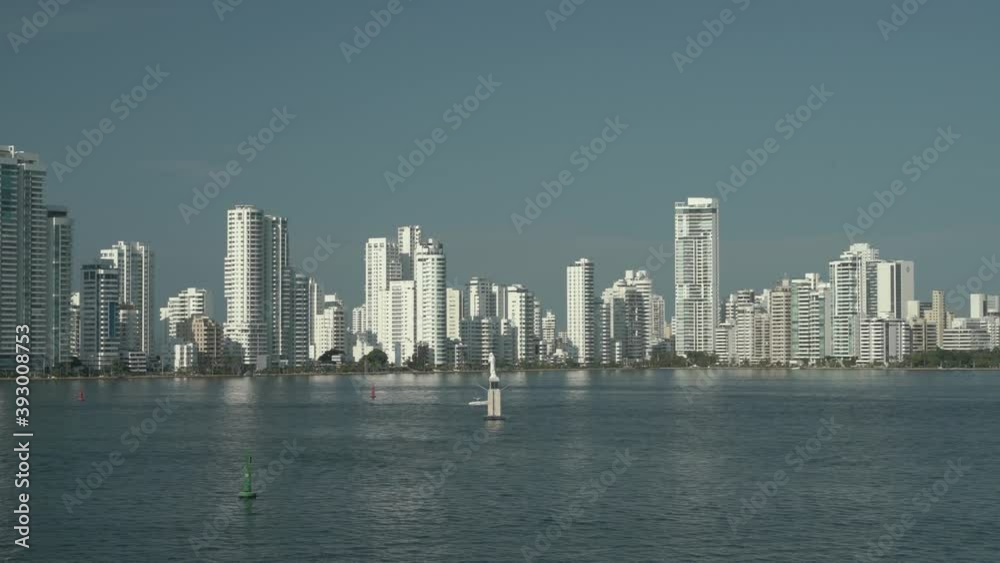 Panning over city sky line and bay of port of Cartagena Colombia. White Skyscrapers and statue of Cartagena a port bay. Panning over city sky line and bay of port of Cartagena Colombia. White Skyscrapers and statue of Cartagena a port bay.