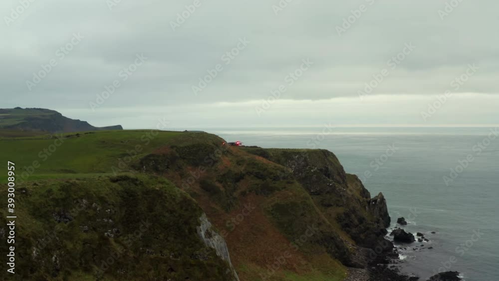 Drone with red lights flies from green rocky cliffs to sea at North Coast of Ireland Drone with red lights flies from green rocky cliffs to sea at North Coast of Ireland