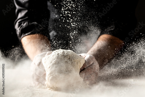 Photo of flour and men hands with flour splash. Cooking bread. Kneading the Dough. Isolated on dark background. Empty space for text