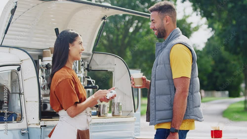 Male customer making contactless payment to female owner of mobile coffee van using smart watch - shot in slow motion Male customer making contactless payment to female owner of mobile coffee van using smart watch - shot in slow motion