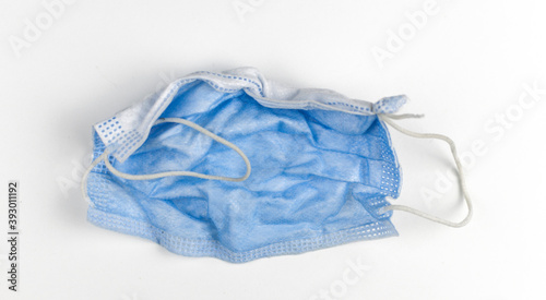 Crumpled used disposable medical face mask on white background
