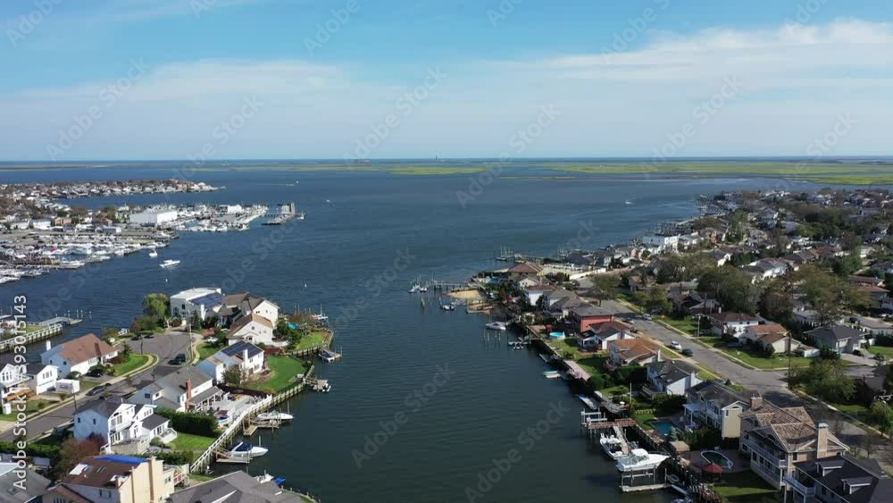 An aerial drone shot over a channel leading out to East Bay on Long Island, NY. The camera dolly in as it heads out towards the horizon. It is a beautiful neighborhood on a sunny day. An aerial drone shot over a channel leading out to East Bay on Long Island, NY. The camera dolly in as it heads out towards the horizon. It is a beautiful neighborhood on a sunny day.