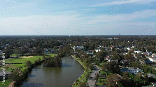 Wallpaper Mural An aerial drone shot over a green pond in a suburban neighborhood on Long Island, NY.  The camera dolly in & boom down over the pond which is surrounded by the little town on a sunny day. Torontodigital.ca