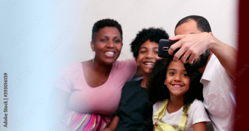 Candid multiracial family taking selfie with phone at home sofa. Interracial parents take group photo Candid multiracial family taking selfie with phone at home sofa. Interracial parents take group photo