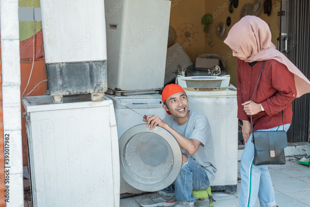 hijab woman takes a broken washing machine to an electronics repairman at an electronics repair shop hijab woman takes a broken washing machine to an electronics repairman at an electronics repair shop