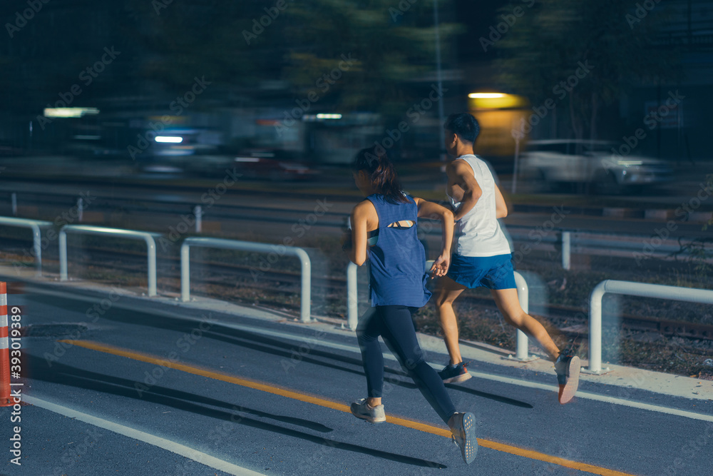 Asian couple jogging in the city streets at night
