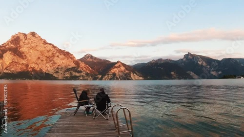 Two tourists sit on the shores of the Traunsee alpine lake