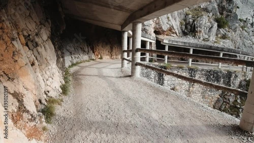A man walks along a fenced mountain road.