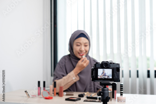 Muslim women making video beauty vlogger bloggers doing a cosmetic makeup tutorial vlog with brushes looking camera Save clips and share them on social media live via the internet Online