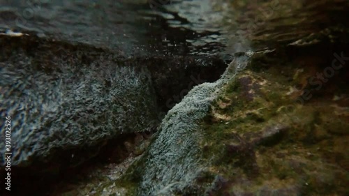 The camera descends into a transparent mountain stream