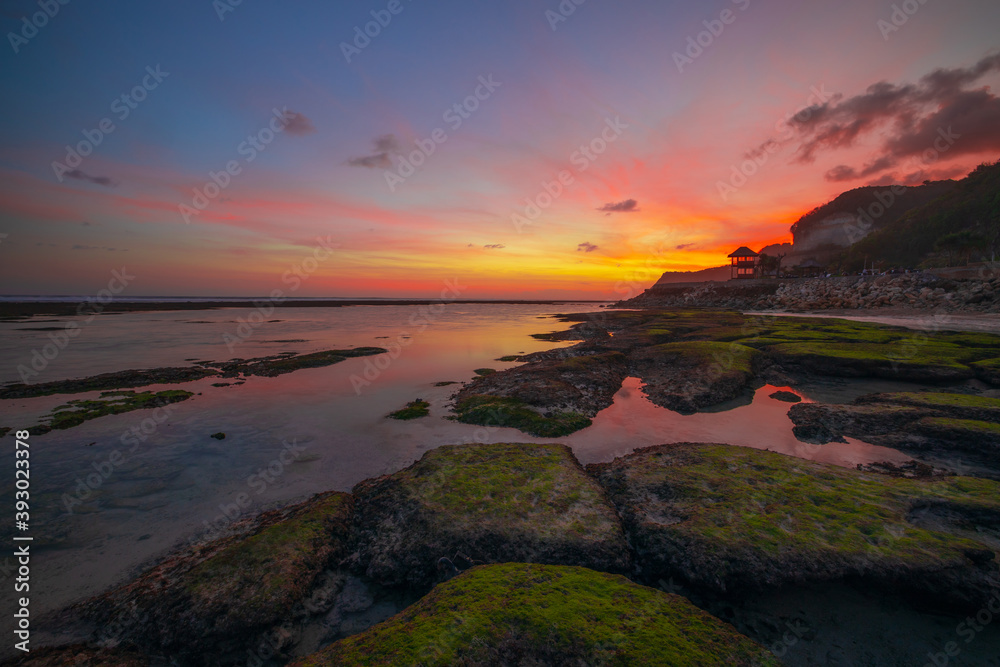 Seascape. Beach with rocks and stones. Low tide. Pink sunset. Slow shutter speed. Soft focus. Melasti beach, Bali, Indonesia