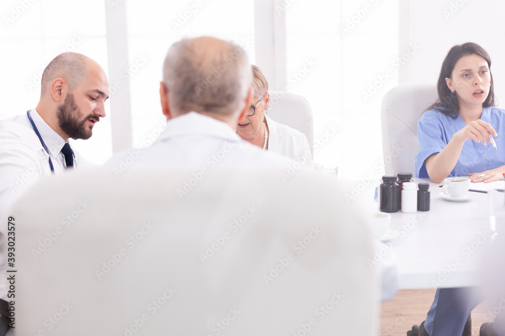 Young expert doctor talking with medical staff in conference room Clinic therapist dicussing with colleagues about disease, medicine professional Young expert doctor talking with medical staff in conference room Clinic therapist dicussing with colleagues about disease, medicine professional