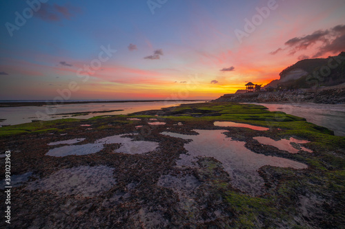 Seascape. Beach with rocks and stones. Low tide. Pink sunset. Slow shutter speed. Soft focus. Melasti beach, Bali, Indonesia