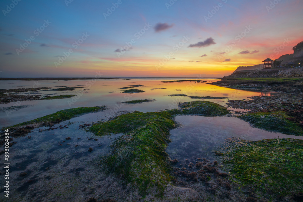 Seascape. Beach with rocks and stones. Low tide. Sunset time. Slow shutter speed. Soft focus. Melasti beach, Bali, Indonesia