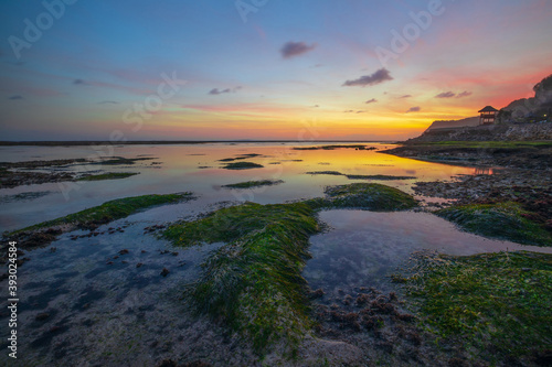 Seascape. Beach with rocks and stones. Low tide. Sunset time. Slow shutter speed. Soft focus. Melasti beach, Bali, Indonesia