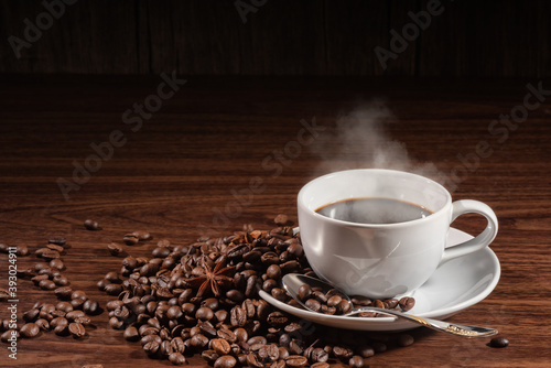 cup of smoky coffee with spoon on coffee beans