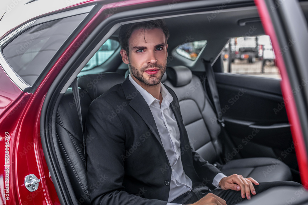 Brown-haired male sitting at backseat of red car