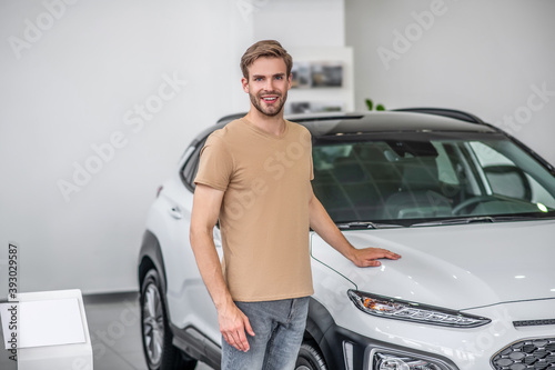 Male customer standing in front of new car, putting his hand on itshood © zinkevych