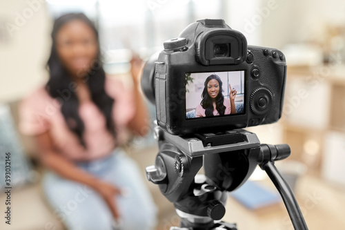 blogging, videoblog and people concept - happy smiling african american female video blogger with camera videoblogging at home