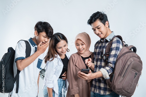 Portrait of happy university youth carrying bags and discussion looking at cell phones on isolated white © Odua Images