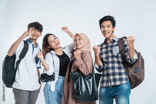 Portrait of Happy College Friends carrying a bag and book excited over white background © Odua Images