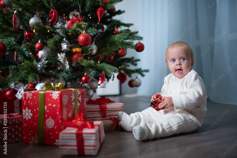 A baby toddler near a Christmas tree A baby toddler near a Christmas tree