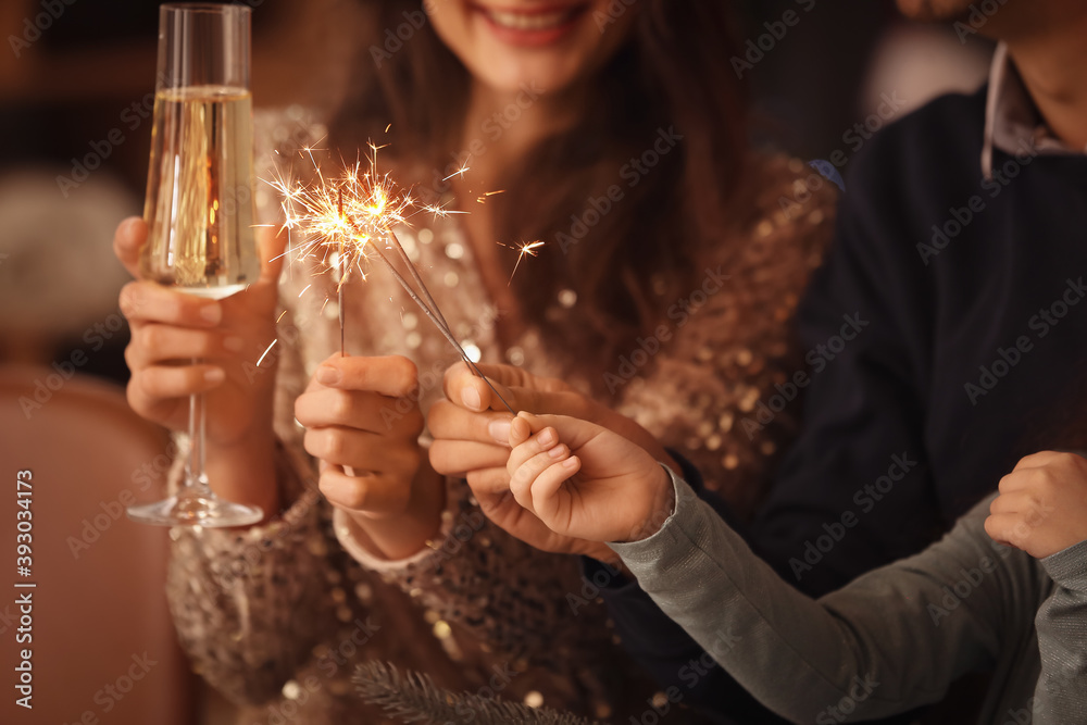 Happy family with sparklers and champagne celebrating Christmas at home - obrazy, fototapety, plakaty 
