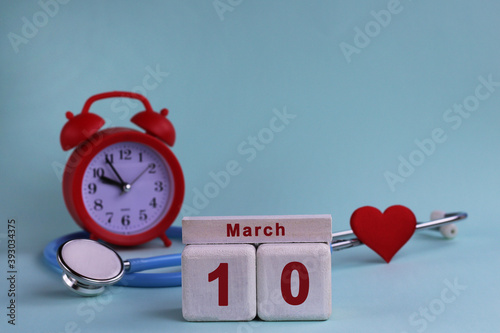 10st March. White wooden calendar blocks with date, clock and stethoscope on a blue pastel background. Selective focus. health concept photo