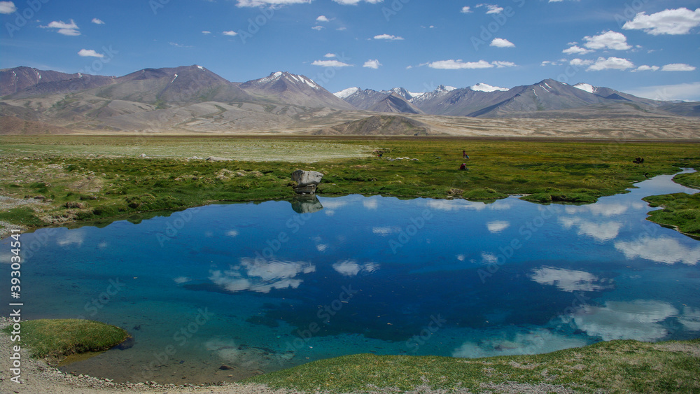 Landscape view of pure turquoise blue water of Ak Balik sacred spring on mountain background, Alichur, Gorno-Badakshan, in the high Tajikistan Pamir
