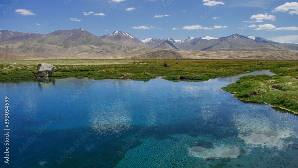 Pure turquoise blue water at Ak Balik sacred spring with mountain background, Alichur district, Gorno-Badakshan region, in the high Pamir of Tajikistan