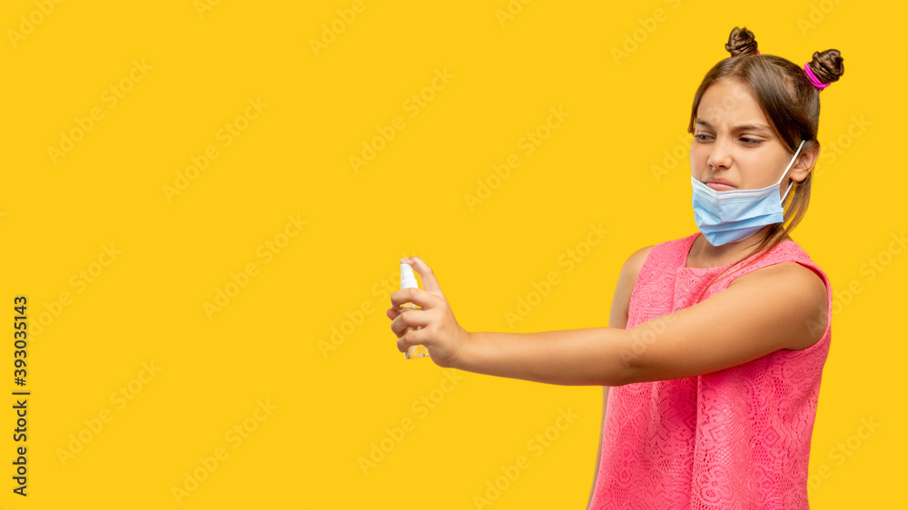 Pandemic anxiety. Covid-19 hygiene. Infection risk. Portrait of disgusted young girl in face mask under chin spraying air with antiseptic isolated on orange copy space background. Pandemic anxiety. Covid-19 hygiene. Infection risk. Portrait of disgusted young girl in face mask under chin spraying air with antiseptic isolated on orange copy space background.