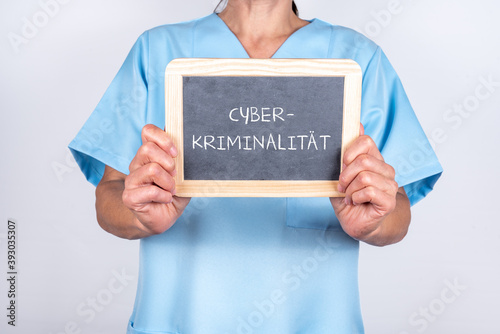 Ärztin oder Krankenschwester hält eine Tafel mit CYBER KRIMINALITÄT hoch